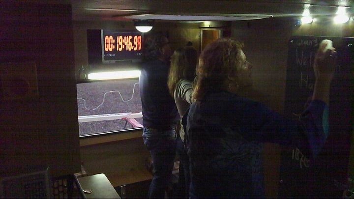 Mensen staan ​​in een donkere ruimte met een digitaal scherm waarop een golvende lijn te zien is.