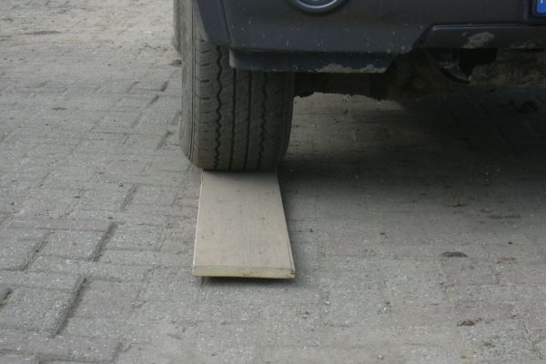 Autoband op een houten plank op een bakstenen ondergrond.