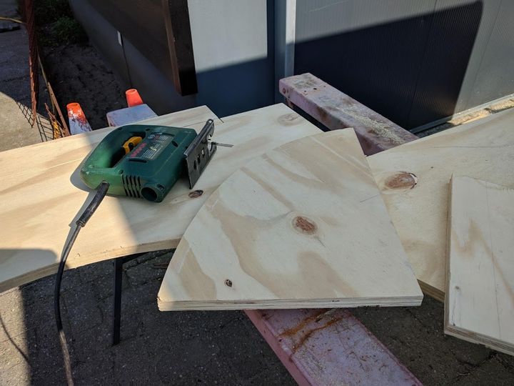Een puzzel op een multiplexplaat met uitgezaagde stukken en een houten steun, buiten.