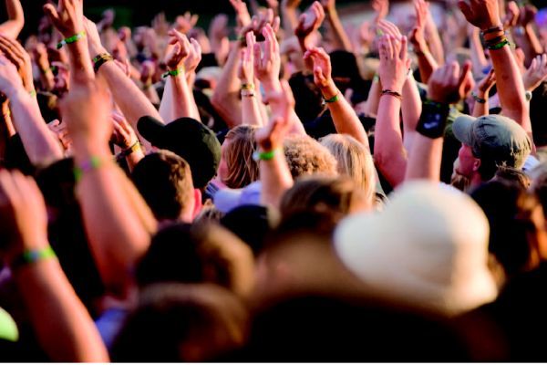 Grote menigte met de armen in de lucht; openluchtconcert.