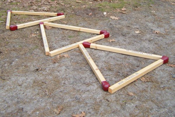 Gigantische luciferhoutjes in een zigzagpatroon op een zanderige ondergrond.