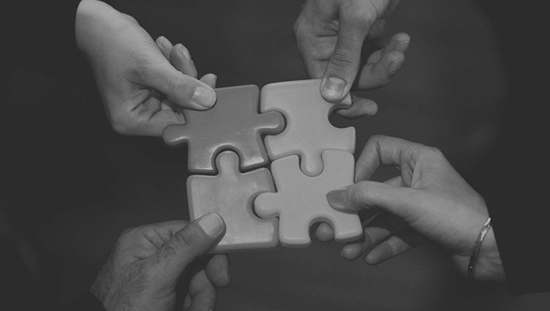 Team members assembling puzzle pieces to represent collaboration and strategic business solutions.
