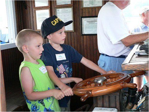 Young boys taking the helm under Captain Sonny's supervision during an exciting dolphin watch (Dolphin & Nature Tour, Hilton Head Island, Sonny C Charters)