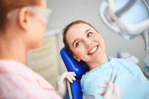 Dental Surgery - Young female sitting in dentist office and looking at her doctor with smile in Joliet, IL Dental Surgery - Young female sitting in dentist office and looking at her doctor with smile in Joliet, IL