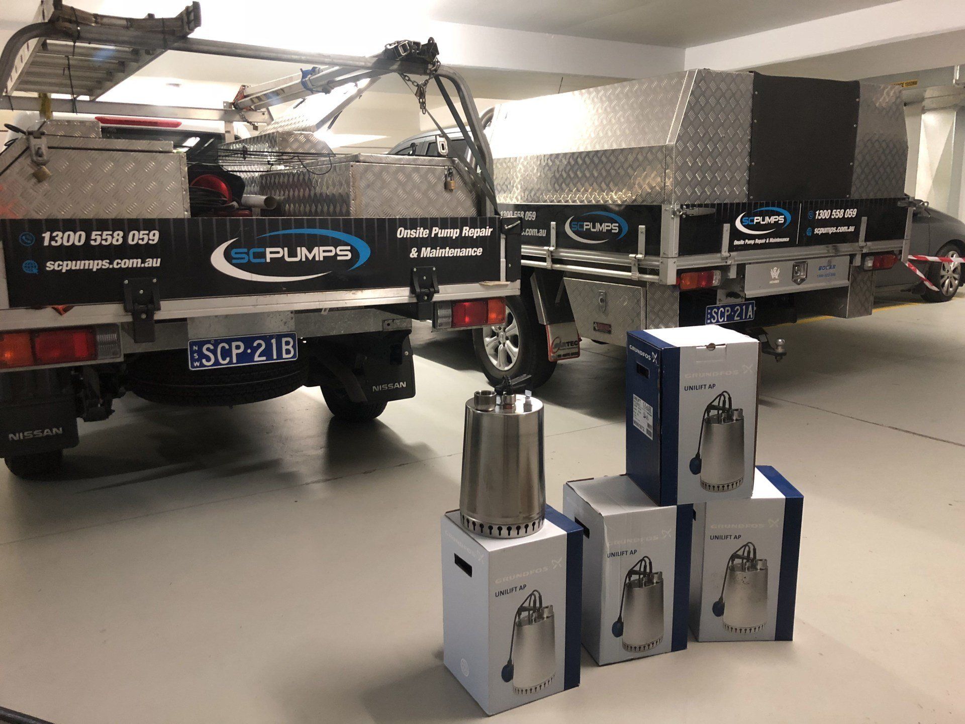 A row of trucks are parked in a garage next to boxes of pumps.