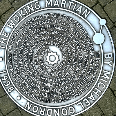 Circular silvery metal plaque by sculpto Michael Condron, embedded in the ground of Woking town centre, Surrey, England . commemorating the town where the HG Wells novel The War Of The Worlds took place as