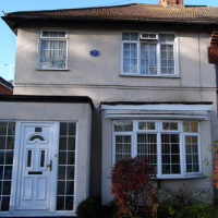 Coloured photograph of cream-rendered house with white-framed windows and white door, the home of writer H.G. Wells in Maybury Road, Woking, Surrey, England, 1895-1896, whilst writing The war Of The Worlds.