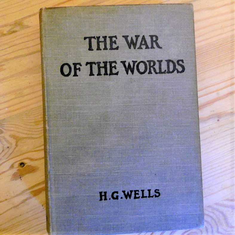 Front cover of a first edition copy of The War Of The Worlds - black lettering on a grey cloth background.