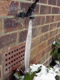 a faucet is covered in ice and water is coming out of it .