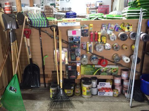 Garage shelf with cleaning tools, brooms, shovels, and paint cans neatly stored against a wall.
