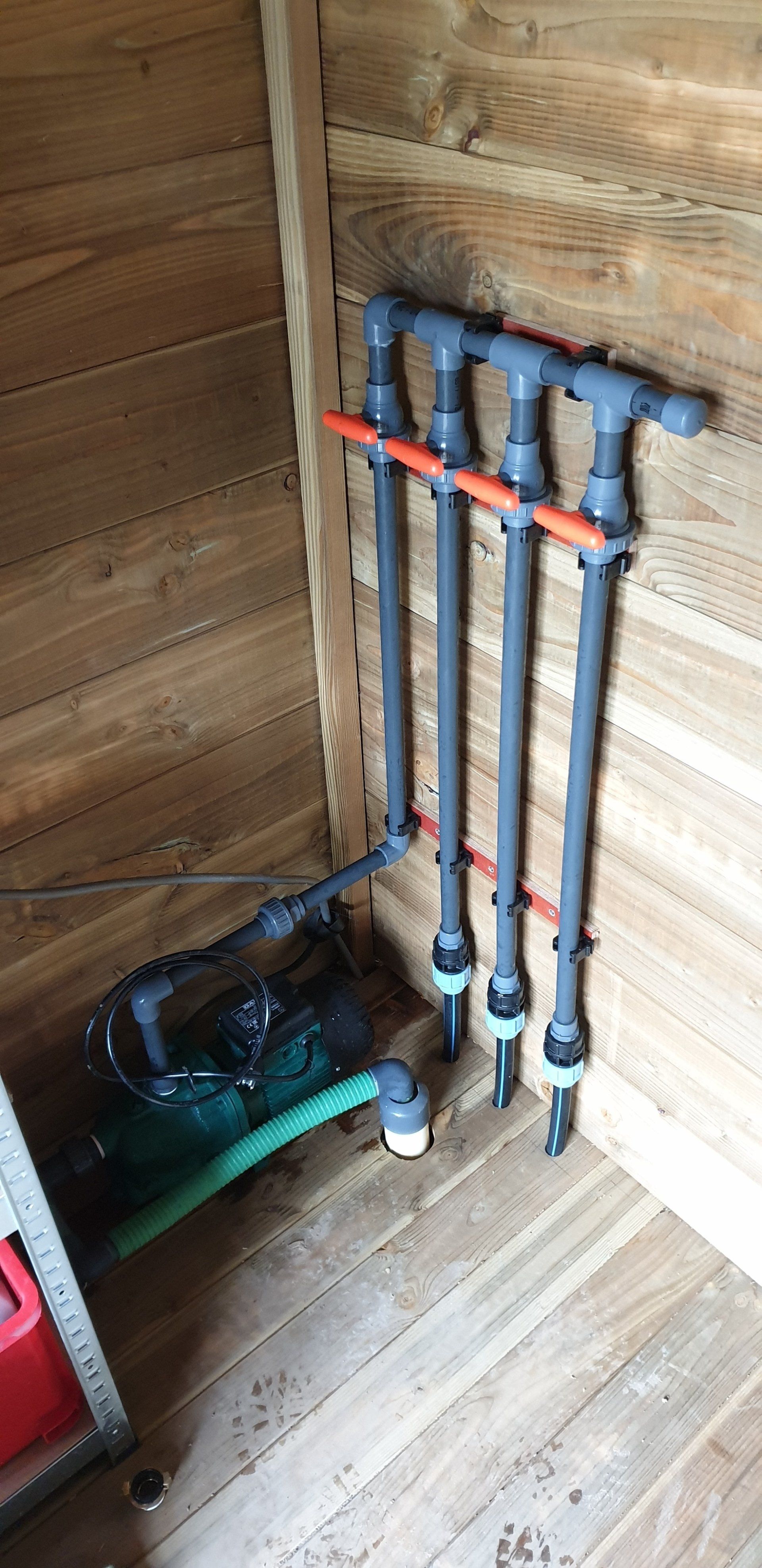 Een sanitairsysteem in een houten constructie met meerdere verticale leidingen die zijn aangesloten op een horizontale leiding.