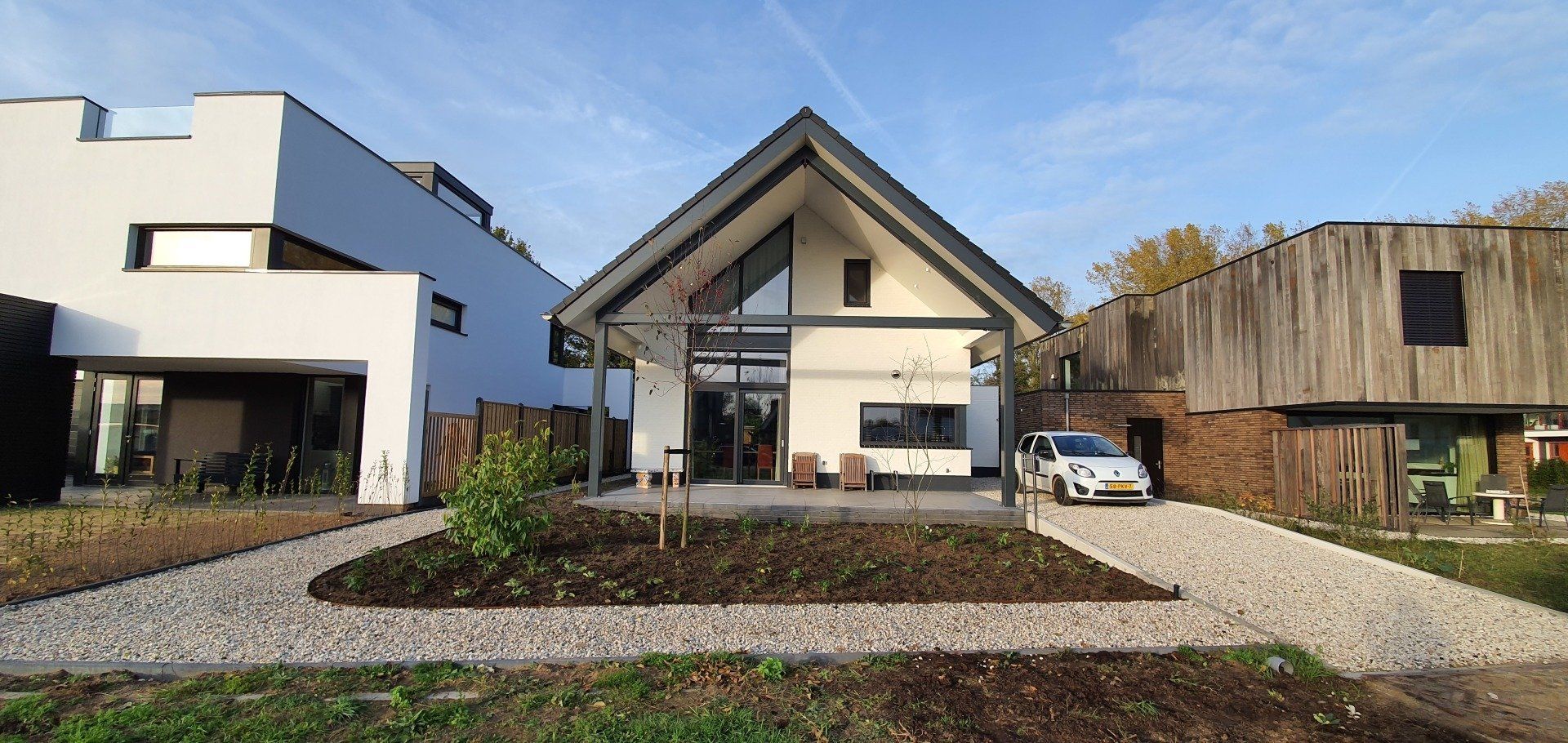 Een modern huis met een carport en een auto op de oprit op een zonnige dag.