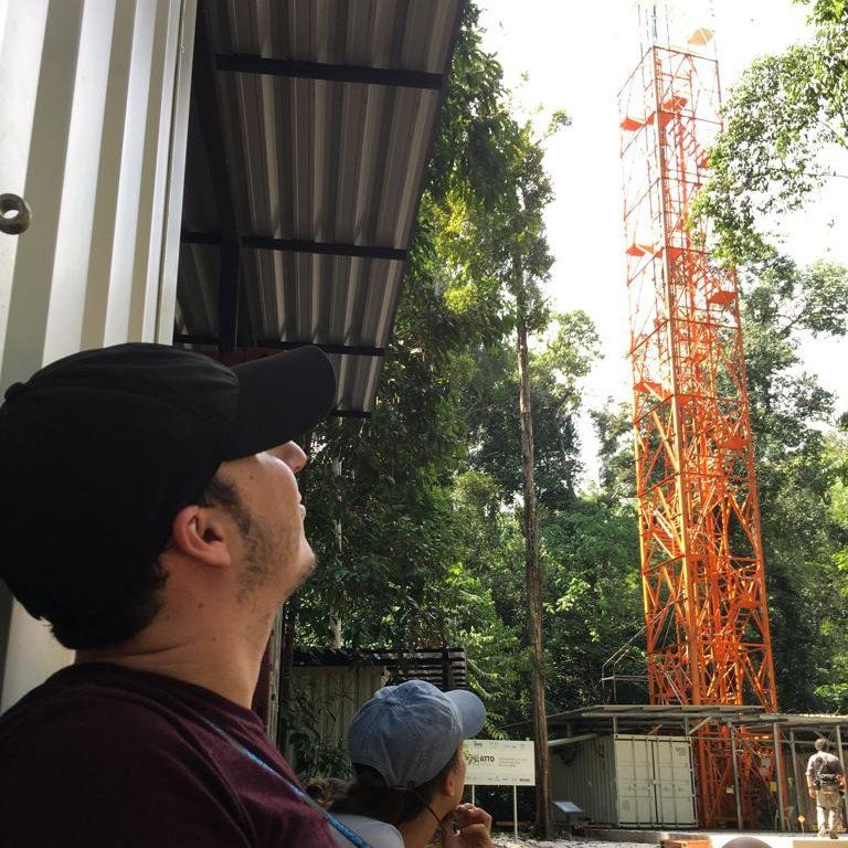 A man in a baseball cap looks up at a tower