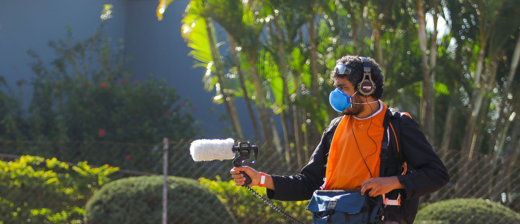 A man wearing a mask and headphones is holding a microphone.