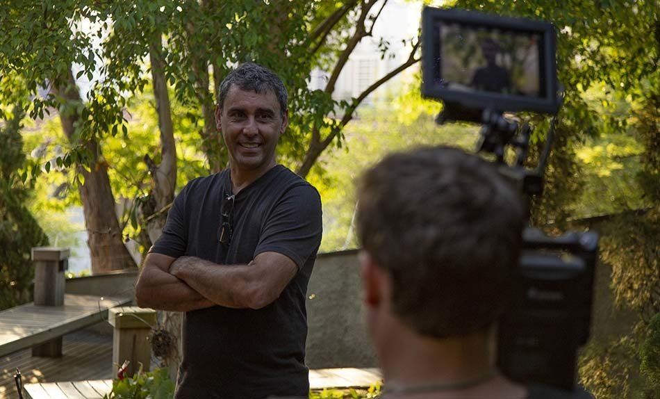 A man is standing in front of a camera with his arms crossed.