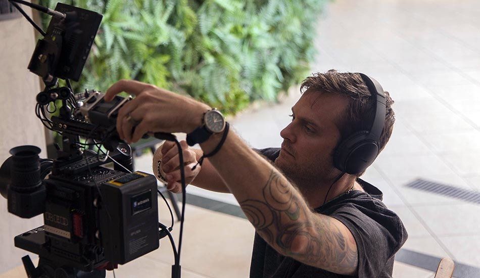 A man wearing headphones is working on a camera.