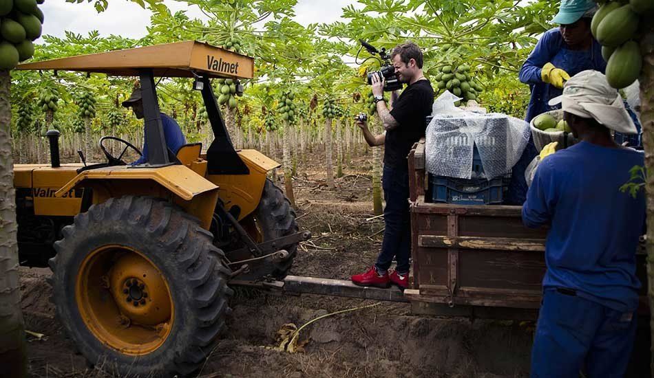A man is taking a picture of a tractor in a field.