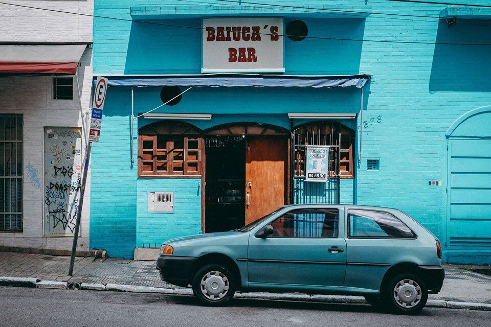A car is parked in front of a blue building that says baiuca 's bar