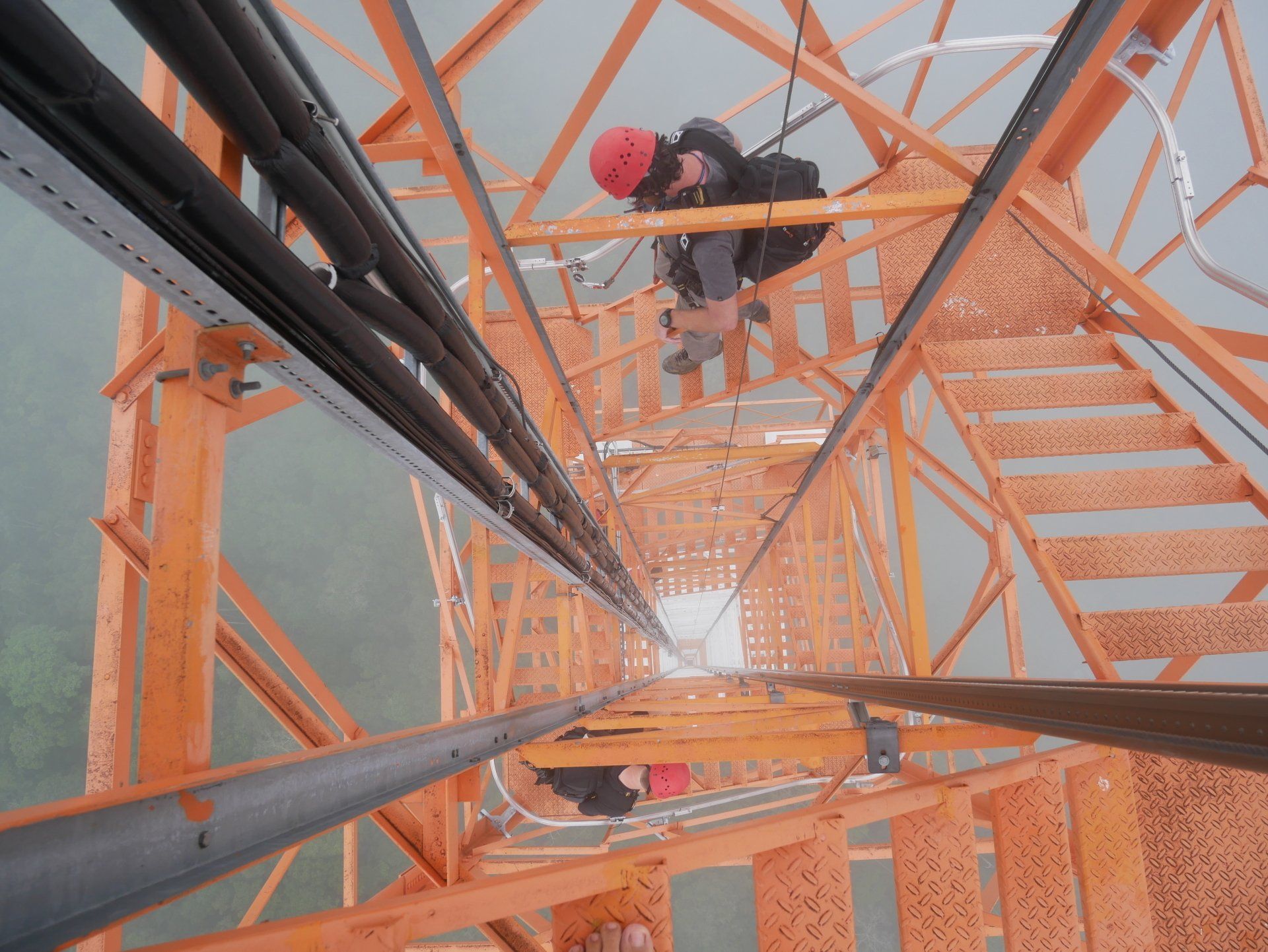 A man in a red helmet is looking down from the top of a staircase.