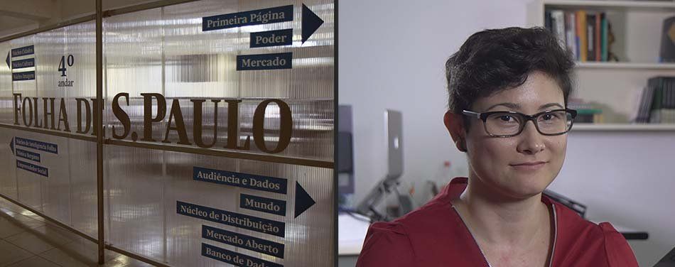 A woman wearing glasses is standing in front of a sign that says paulo.