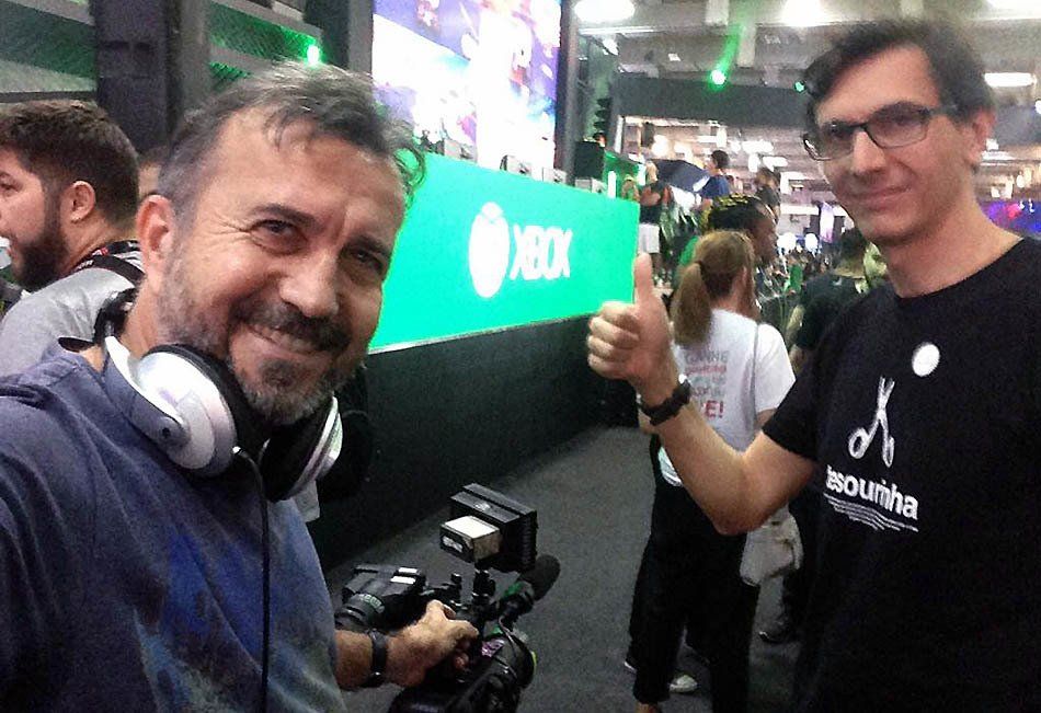 Two men are posing for a picture in front of an xbox sign