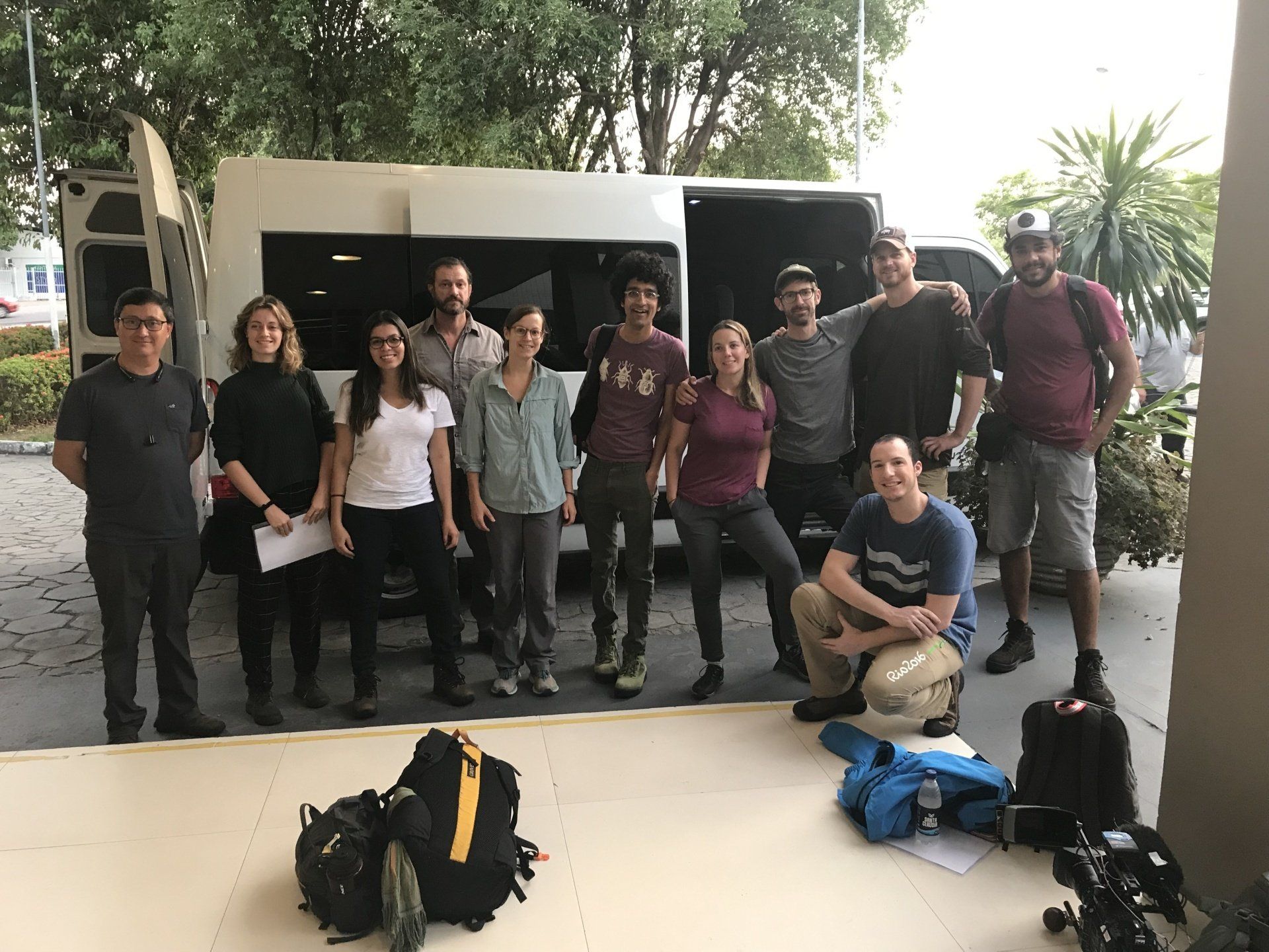 A group of people are posing for a picture in front of a van.