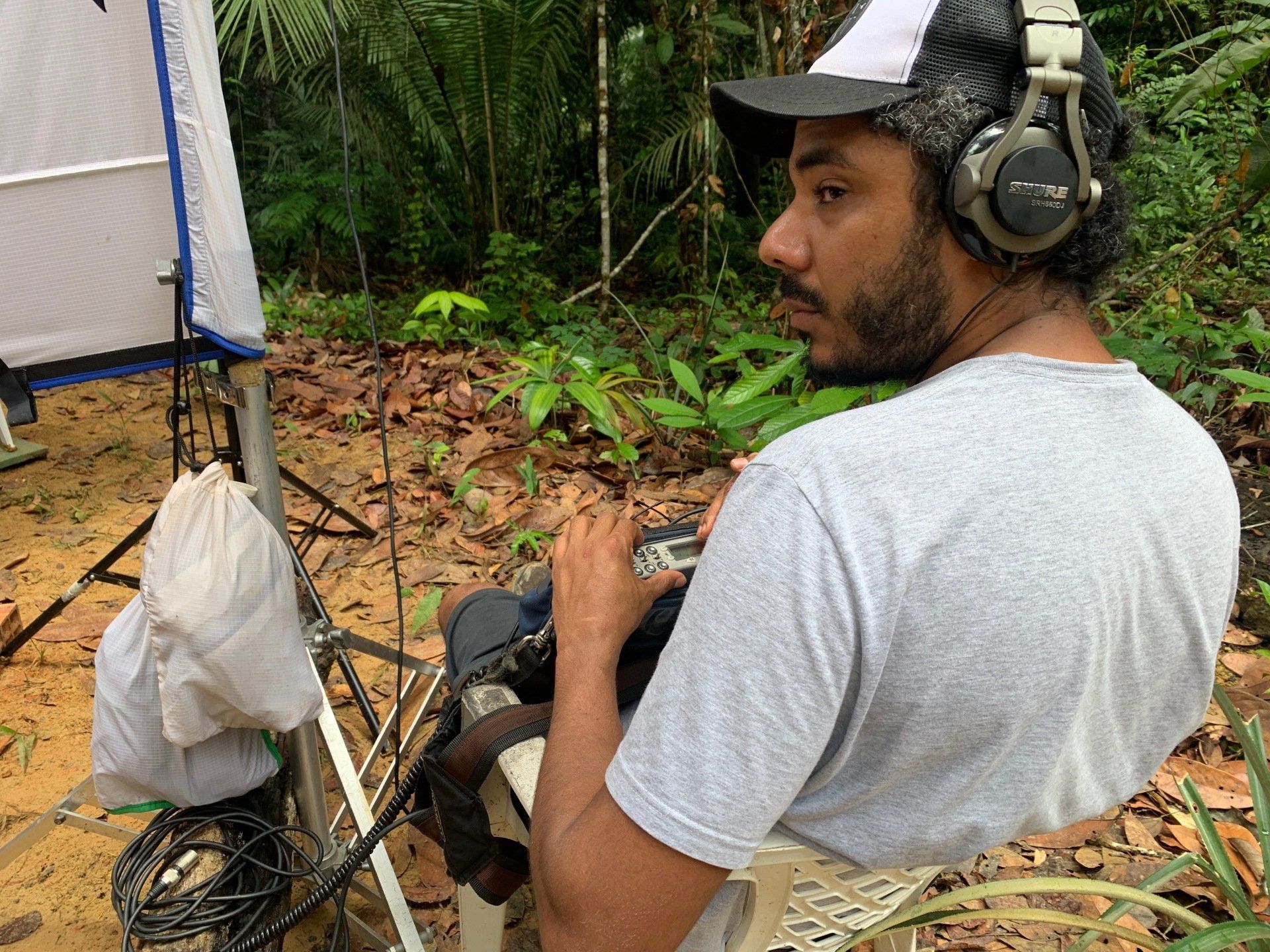 A man wearing headphones and a hat is sitting in a chair