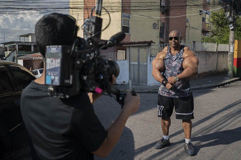 A man is standing in front of a camera while a cameraman takes a picture of him.