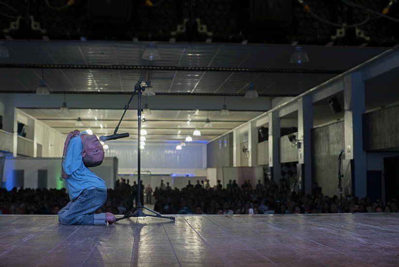 A man is kneeling on a stage in front of a microphone.