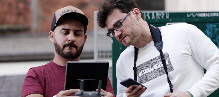 Two men are standing next to each other looking at a remote control.