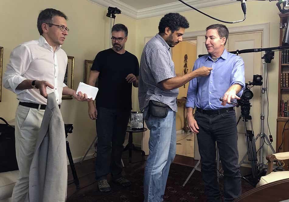 A group of men are standing in a living room talking to each other