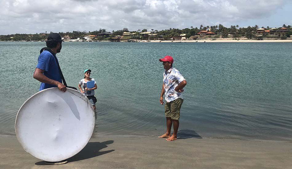 A man is standing on a beach holding a large white plate.