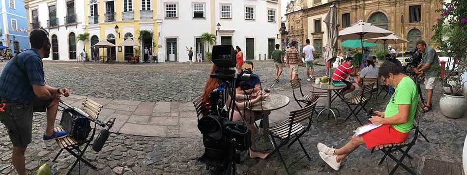 A group of people are sitting at tables in a city square.