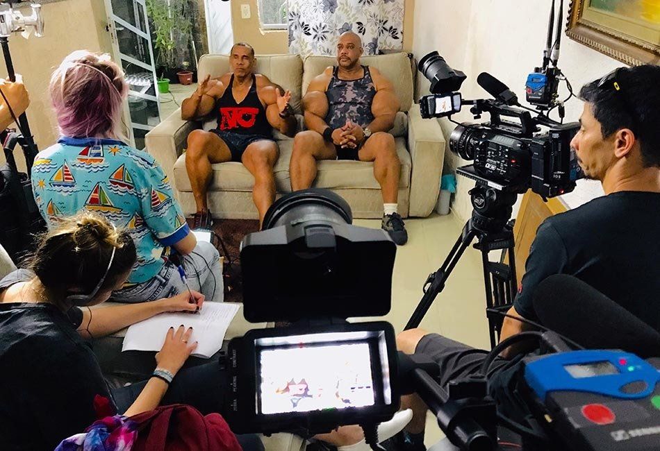 A group of people are sitting on a couch in front of a camera.