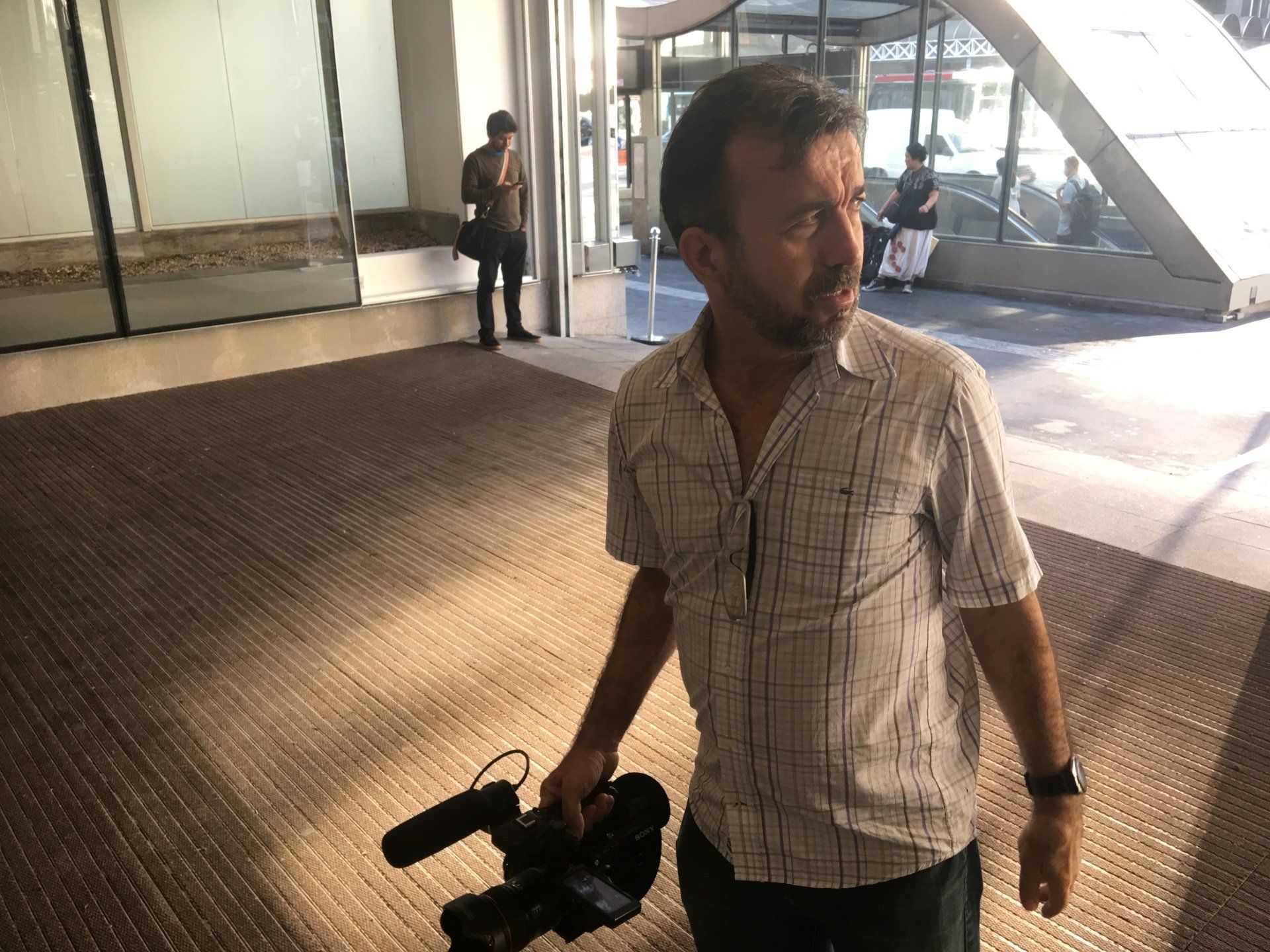 A man is walking with a camera in his hand.