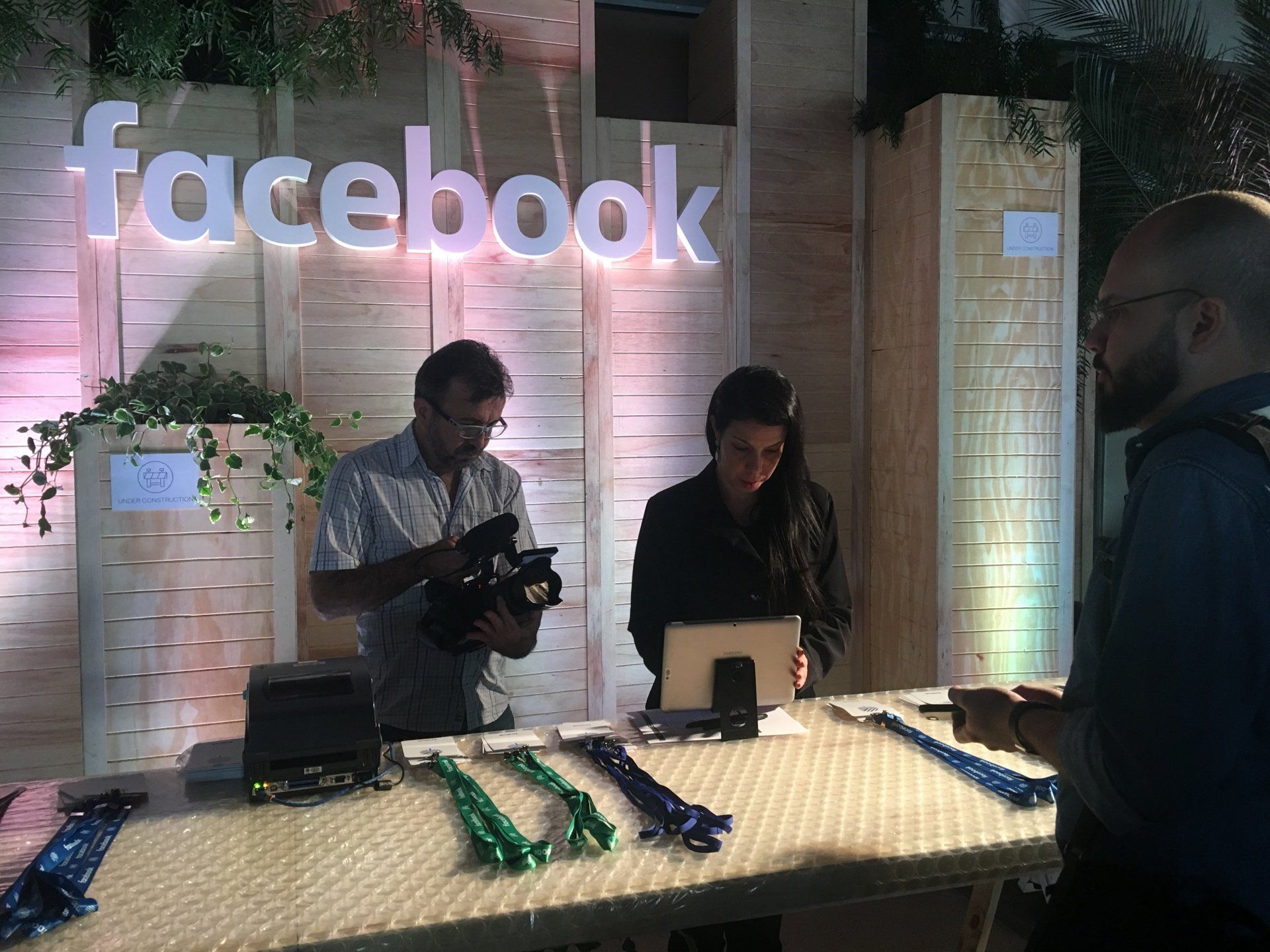 A man is holding a camera in front of a facebook sign