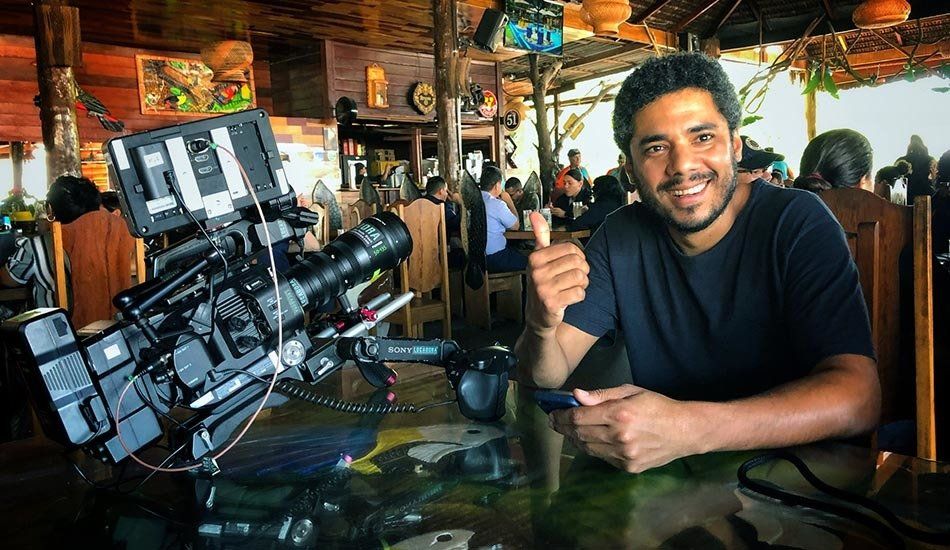 A man is sitting at a table in front of a camera.