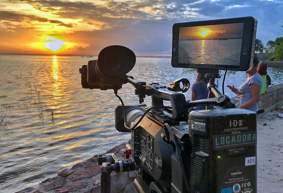 A camera is sitting on a beach with a sunset in the background