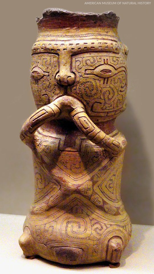 Burial urn, Marajoara culture, ©American Museum of Natural History A statue of a man with a pipe in his mouth is sitting on a table.