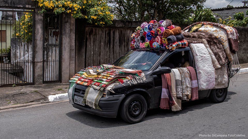 A car is loaded with blankets and balloons on top of it.