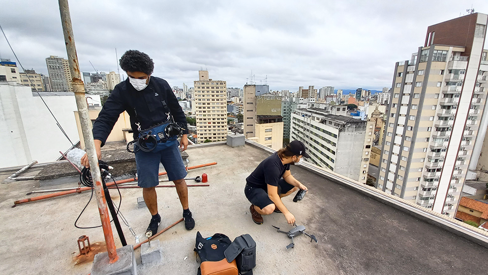Story Productions films on location in São Paulo Two men are working on the roof of a building.
