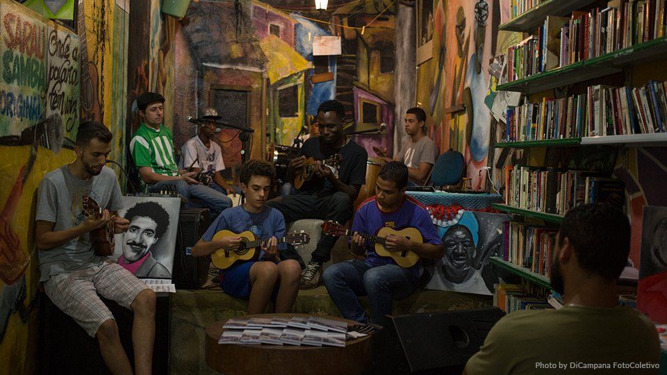 A group of men are sitting on a couch playing guitars in a room.