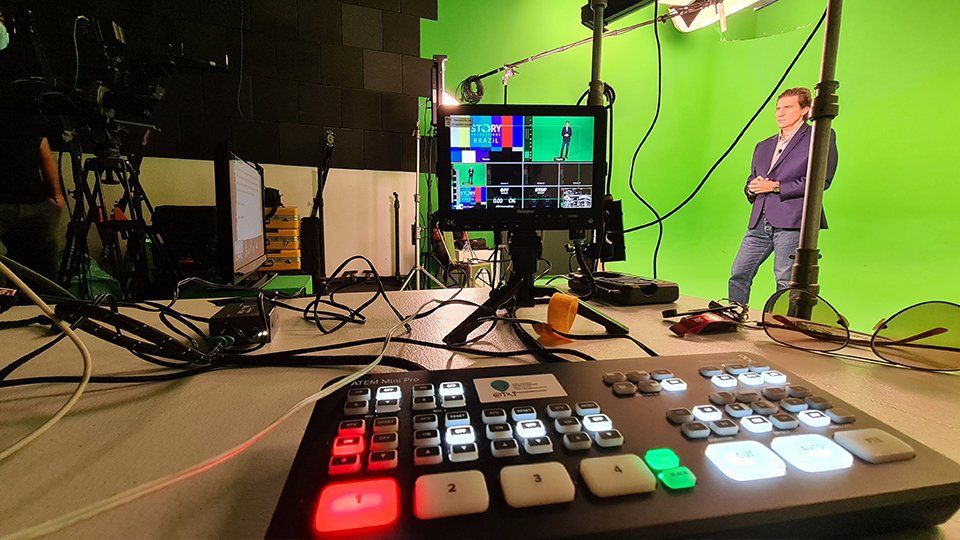 Story Productions films and transmits live from a location A man is standing in front of a green screen in a studio.