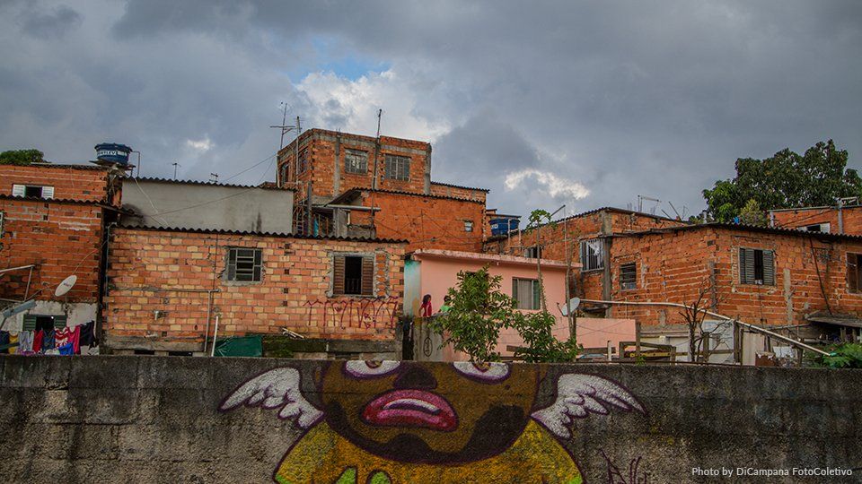 Photo by Di Campana FotoColectivo A graffiti painting of a man with wings on a wall in front of a brick building.