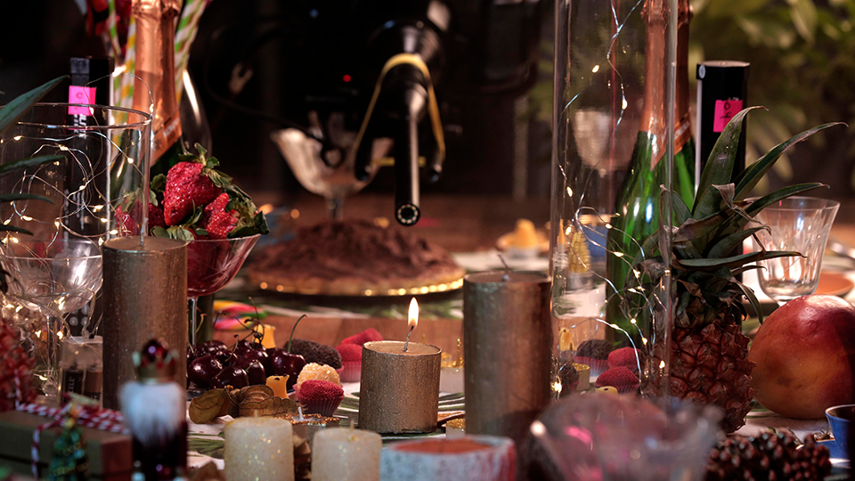 A table with candles , fruit , glasses and a cake on it.
