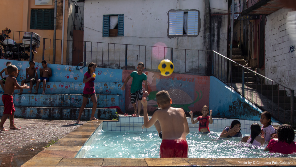 A group of children are playing with a soccer ball in a pool.