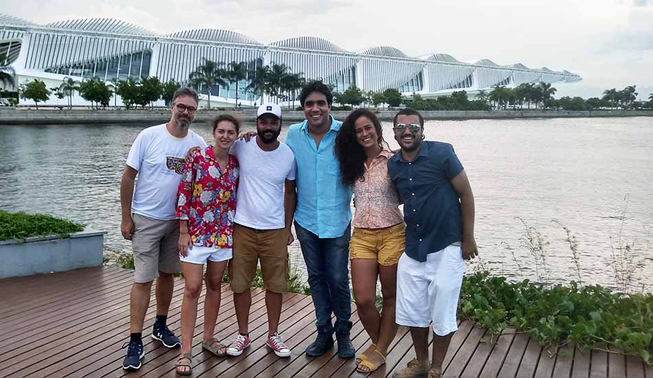 A group of people are posing for a picture in front of a body of water.