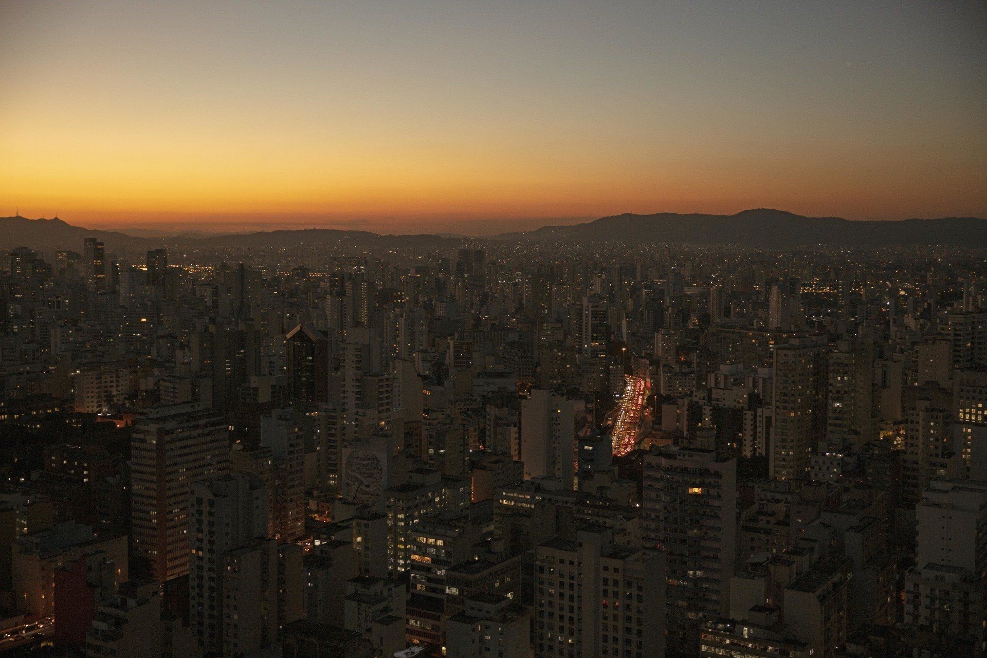 An aerial view of a city at sunset with mountains in the background.