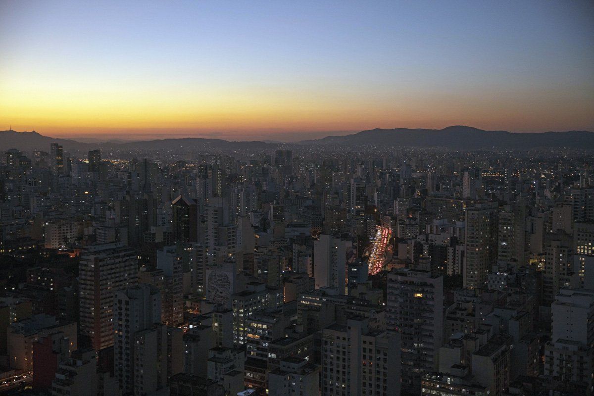 An aerial view of a city at night with a sunset in the background.