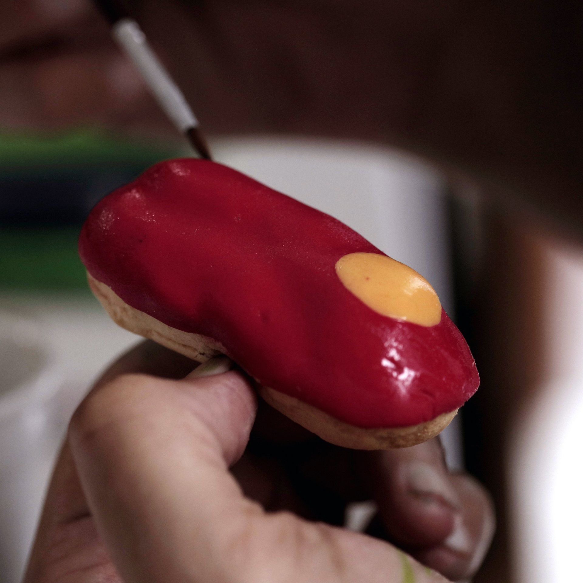Food Styling A person is holding a red donut with a yellow center